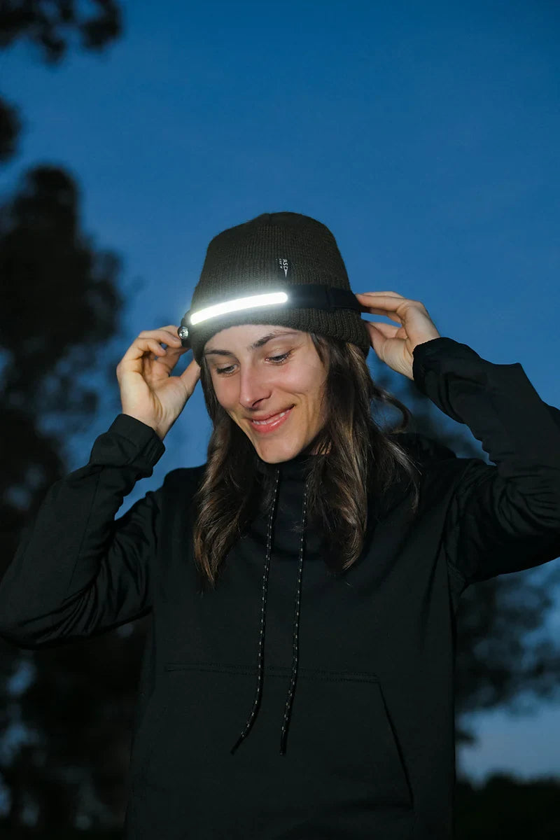 Eine Frau richtet ihre Stirnlampe in der Abenddämmerung aus
